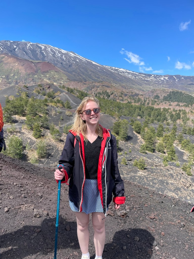 Journalist Olivia Emily standing on Mt Etna in hiking gear
