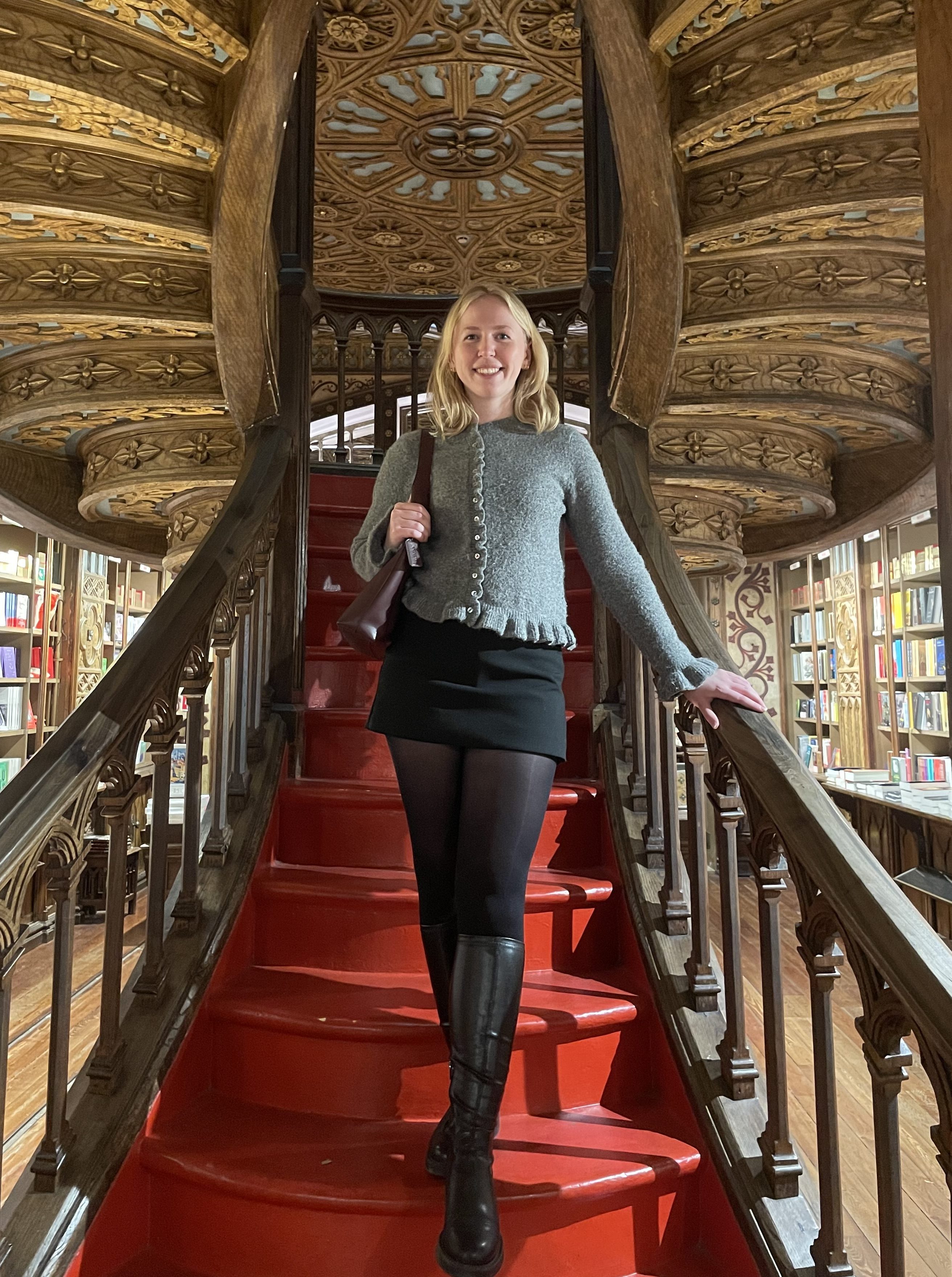 Journalist Olivia Emily standing on an ornate red staircase